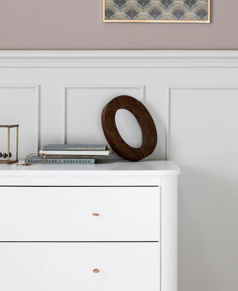 White dresser with decorative items against a gray wall with a framed picture.