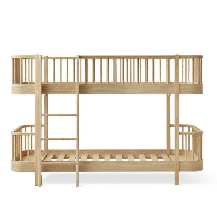 Oliver furniture Low wood bunk bed frame with an upper loft bed, a ladder, and a lower single bed frame made in Oak, shown against a plain white background.