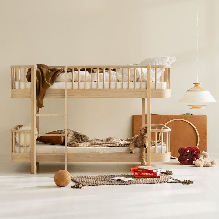 Oliver furniture oak Wooden bunk bed in a minimalistic room with toys and books on the floor.