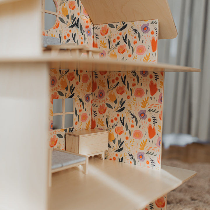 Wooden dollhouse with floral wallpaper and furniture on a neutral background