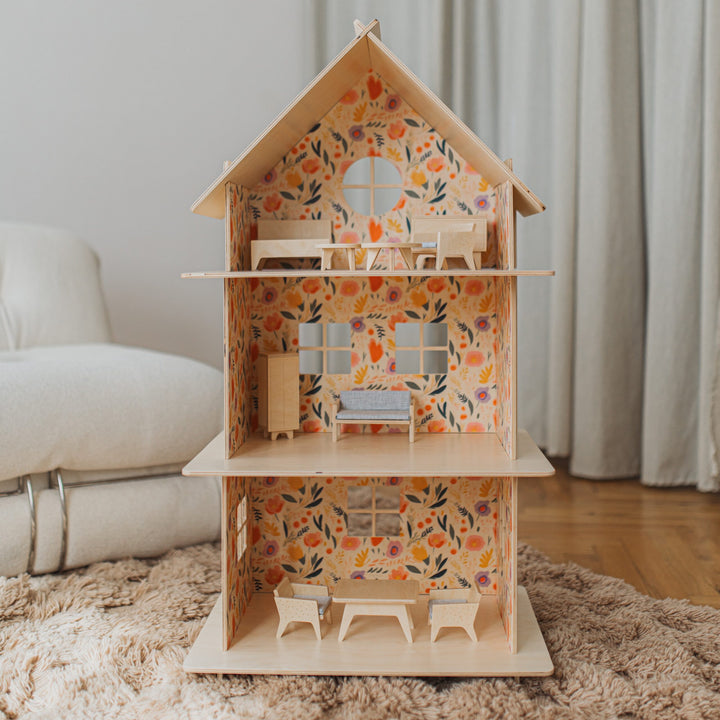 Wooden dollhouse with floral pattern on a rug in a room.